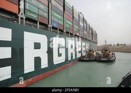 (210325) -- LE CAIRE, le 25 mars 2021 (Xinhua) -- des navires de secours travaillent sur le site d'un navire à conteneurs piégé sur le canal de Suez en Égypte le 25 mars 2021. La navigation dans le canal de Suez a été suspendue temporairement jusqu'à la fin des travaux de re-flottaison sur un navire ancré dans un nouveau cours, a déclaré jeudi Oussama Rabie, président de l'Autorité du canal de Suez (SCA). Le navire à conteneurs portant le drapeau du Panama, d'une capacité de 224,000 tonnes, a été mis à la terre tôt mardi dans le nouveau passage après avoir perdu la capacité de conduire dans des vents violents et une tempête de poussière, a déclaré l'ACR mercredi dans une déclaration. (Auteur du canal de Suez Banque D'Images