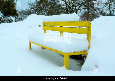 Banc en bois jaune dans le parc recouvert de neige, vue en hiver Banque D'Images