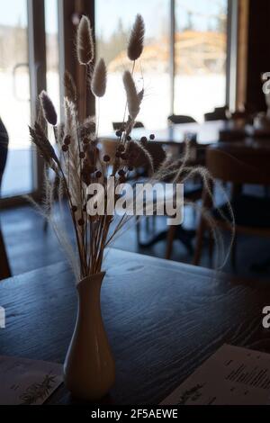 Un bouquet de fleurs séchées se trouve dans un vase une table contre t Banque D'Images