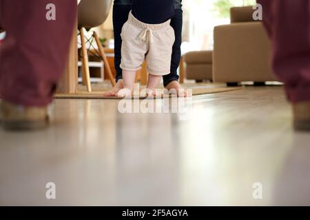 Portrait en gros plan de bébé garçon apprenant à marcher avec l'aide de la mère à la maison Banque D'Images