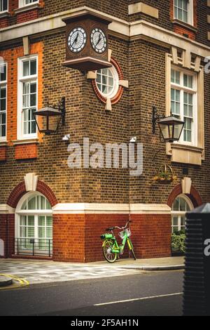 Vélo vert couché sur un mur quelque part à Londres.Le four est verrouillé en toute sécurité.Arrière-plan Contrasty Banque D'Images