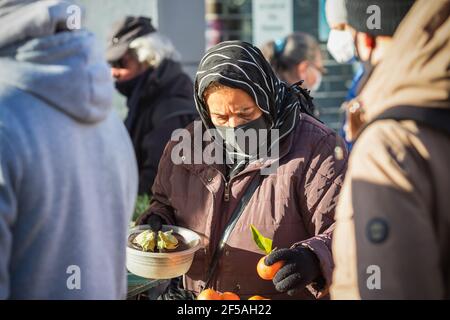 Londres, Royaume-Uni - 5 février 2021 - UNE femme asiatique britannique portant un masque facial lorsqu'elle fait du shopping dans un stand de produits extérieurs situé dans la rue Wood Green High Street Banque D'Images