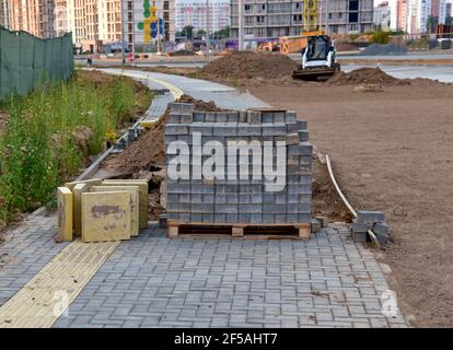 Processus d'installation de briques de pavage dans la zone piétonne de la ville. Pose de dalles et de bordures sur le chantier. Crier le sable pour l'installation Banque D'Images