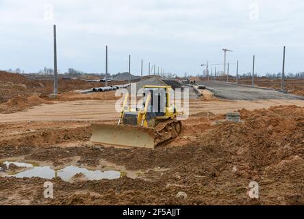 Le bulldozer déplace le gravier pendant les travaux sur route sur le chantier. Pierres de nivellement de bouteur pour la pose d'asphalte sur une nouvelle autoroute. Machines lourdes pour la terre- Banque D'Images