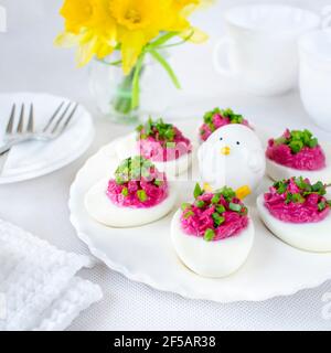 Œufs durs farcis avec de la pâte de betteraves et saupoudrés de ciboulette. Banque D'Images