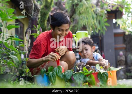 Le fils et sa mère passent du temps ensemble dans le jardin. Ils ont planté des bétel dans des pots colorés. L'atmosphère semblait chaleureuse et gaie Banque D'Images