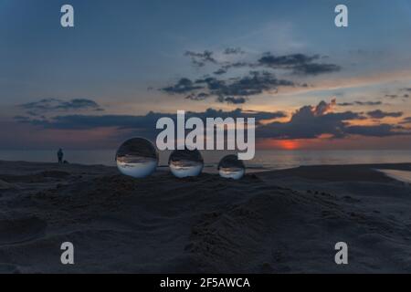 Trois boules de cristal claires de trois tailles sont sphérique révèle vue paysage avec sphérique placé sur le sable à Karon Beach pendant le coucher du soleil. Banque D'Images