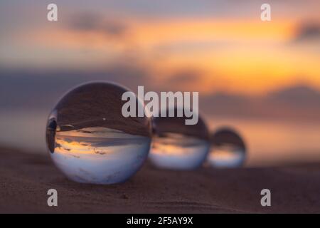 Trois boules de cristal claires de trois tailles sont sphérique révèle vue paysage avec sphérique placé sur le sable à Karon Beach pendant le coucher du soleil. Banque D'Images