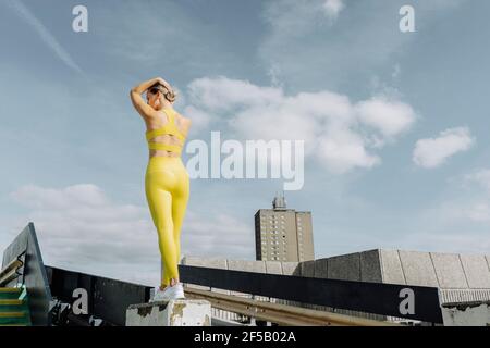 femme sportive attrayante portant des vêtements d'activité jaunes debout à l'extérieur, sur le toit. Banque D'Images