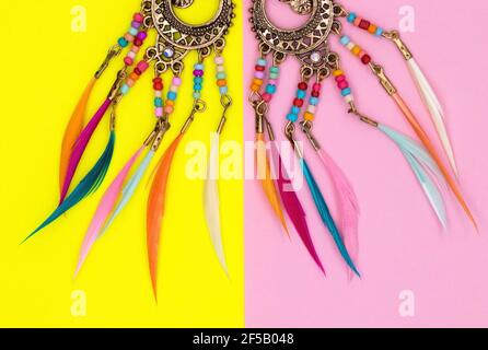 Décorations ethniques sur des feuilles de papier de couleur.bijoux pour femmes avec une base en métal rond, avec perles et plumes colorées boucles d'oreilles anneaux Amulets. Rose a Banque D'Images