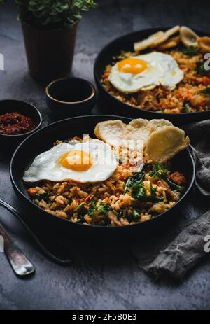 Nasi Goreng, riz frit indonésien, servi avec une sauce soja, une sambal à la pâte de piment, un côté ensoleillé vers le haut et des craquelins kérapuk Banque D'Images