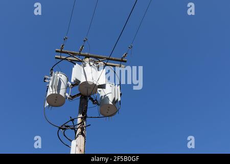 Grand poteau électrique en bois avec trois transformateurs contre un ciel bleu clair et profond, aspect horizontal Banque D'Images