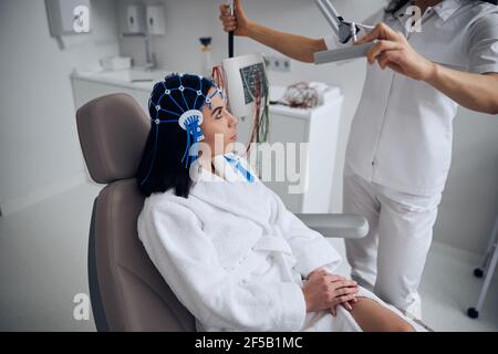 Jeune femme assise sur la chaise pendant la procédure EEG Banque D'Images