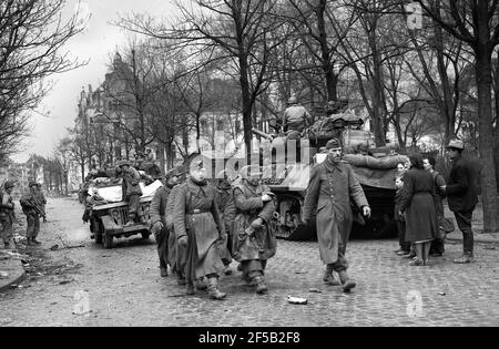 Cologne, Allemagne 1945 escorte de troupes américaines a capturé des soldats allemands après qu'ils se sont rendus sous la surveillance des populations locales pendant la Seconde Guerre mondiale à la suite d'un violent bombardement de la ville. Seconde guerre mondiale : défaite allemande victoire alliée Deutschland les années 1940 rendent l'Europe la destruction de l'histoire européenne Banque D'Images