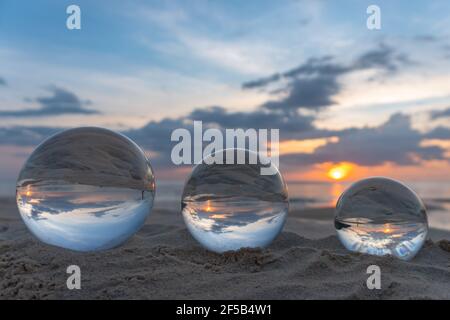 Trois boules de cristal claires de trois tailles sont sphérique révèle vue paysage avec sphérique placé sur le sable à Karon Beach pendant le coucher du soleil. Banque D'Images