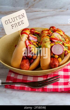 Chiens chipants de fantaisie recouverts de radis, de ketchup à la moutarde et de vert sauce sur des petits pains sans gluten Banque D'Images