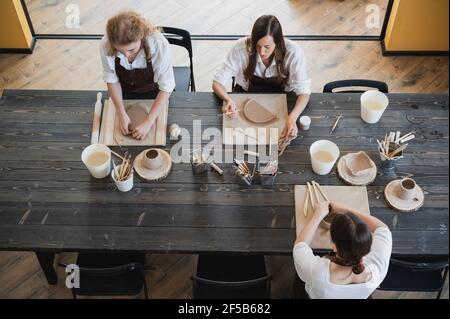 Femmes travaillant dans un studio de poterie, souriant et parlant. Atelier de céramique, cours de maître en poterie Banque D'Images