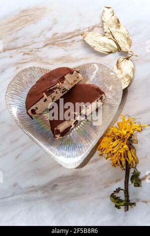 Bar à glace aux cerises enrobées de chocolat servi sur un coeur romantique Assiette en forme de Saint-Valentin Banque D'Images