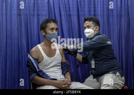 Un travailleur de la santé injecte une dose du vaccin Sinovac COVID-19 à un travailleur au cours d'une campagne de vaccination de masse pour les travailleurs du secteur public au Bureau de l'Agence d'information géospatiale à Bogor.l'Indonésie en est actuellement à la deuxième phase de la vaccination de masse contre le covid-19. Dans cette deuxième phase, le gouvernement indonésien cible 38.5 millions de personnes, dont 16.9 millions de travailleurs dans les secteurs publics et 21.6 millions de citoyens âgés, ainsi que des travailleurs dans les secteurs de l'accueil, des transports, du tourisme et des médias de masse. Banque D'Images