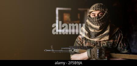 Soldat arabe dans un headaddress du keffiyeh national avec des armes dans ses mains. Homme musulman avec des fusils sur le noir Banque D'Images