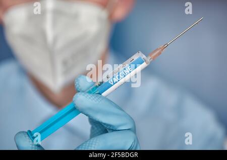 Gros plan d'un chercheur avec un visage masksholding d'une seringue avec le vaccin Covid-19. Banque D'Images