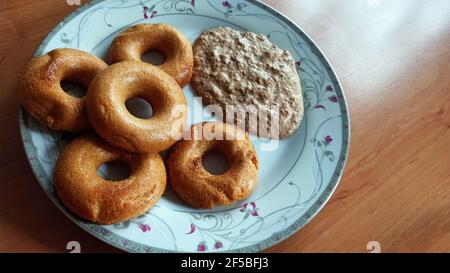 Cinq beignets en forme de beignet Medhu Vada, Chili Pakora avec chutney de noix de coco.délicieuse cuisine du sud de l'Inde sur une assiette blanche sur fond de bois. Banque D'Images