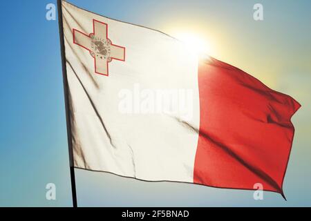 Drapeau de Malte agitant sur le vent devant le soleil Banque D'Images