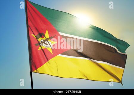 Drapeau mozambicain agitant sur le vent devant le soleil Banque D'Images