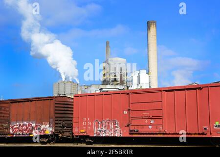 De vieux wagons rouges avec des graffitis bloquent la vue sur les installations de Evergreen Paper Mill, mais pas les cheminées fumantes à Canton, NC, USA Banque D'Images