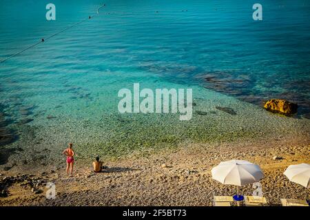 Vue arrière de l'homme et de la femme en maillot de bain en regardant la belle mer Adriatique bleu vert de la plage de galets de Baska, île de Krk, Croatie Banque D'Images