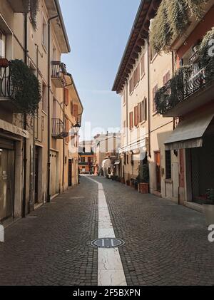 Bardolino, Italie. 25 mars 2021. Le cinquième jour de printemps, avec la via BG.Giuseppe Garibaldi centre dans la ville de Bardolino, le midi (11,41 cet). Chaque année, un millier de touristes sont arrivés au printemps à la ville du lac de Garde. Aujourd'hui, les rues sont désertiques, queues, bar, restaurants fermés pendant la troisième vague de l'épidémie de Covid-19, à Bardolino, Italie, 25 mars 2021. Credit: ALEJANDRO SALA/Alamy Live News Banque D'Images