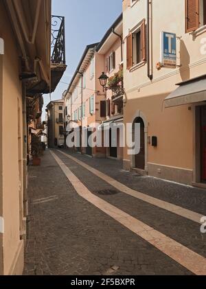 Bardolino, Italie. 25 mars 2021. Vue sur la via Palestro au centre-ville de Bardolino, près de Vérone. Célèbre ville touristique au lac de Garde à midi, le cinquième jour du printemps. Les magasins, le bar, les queues sont fermés, les rues sont désertes, pendant la troisième vague de l'épidémie de Covid-19. Le verrouillage local de plus en plus répandu amènera une grande partie de l'Italie dans les zones rouges. À Bardolino, Italie, 25 mars 2021. Credit: ALEJANDRO SALA/Alamy Live News Banque D'Images