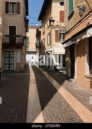 Bardolino, Italie. 25 mars 2021. Vue sur la via Alberto dans le centre ville de Bardolino, à midi (11,41 cet). Chaque année, un millier de touristes arrivent au printemps, aujourd'hui le cinquième jour du printemps, ses rues sont vides, et le commerce fermé pendant la troisième vague de l'épidémie de Covid-19. À Bardolino, Italie, 25 mars 2021. Credit: ALEJANDRO SALA/Alamy Live News Banque D'Images