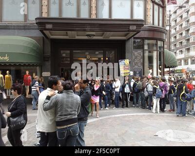 Scène de rue à l'extérieur de Harrod's à Londres, avec beaucoup de gens et un manifestant contre la fourrure avec bannière Banque D'Images