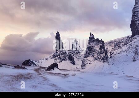 Old Man Storr, Isle Skye, Écosse. Hiver, montagne très enneigée dans un lever de soleil très puissant. Premier matin lumières parmi les nuages Banque D'Images