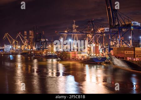 Gdynia, Pologne - 09.01.2017: Grues de chargement de navires fonctionnant avec des conteneurs lourds dans le port de Gdynia, Pologne. Chargement de gros navires de fret la nuit Banque D'Images