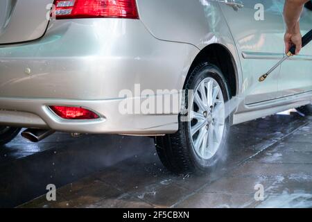 Gros plan photo d'un homme mains lave sa voiture avec une grande tête d'eau d'un karcher et lavage de voiture avec du savon. Nettoyage et désinfection. Lavage de voiture Banque D'Images