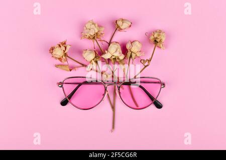 verres roses en couleurs. flat lay. Glamour et style. Lunettes pour femmes. Verres roses sur fond rose décorés de roses séchées Banque D'Images