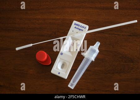 Kit d'auto-test d'antigène rapide Covid-19 à domicile avec écouvillons nasaux, tube et dispositif de détection avec résultat négatif sur une table en bois marron, cop Banque D'Images
