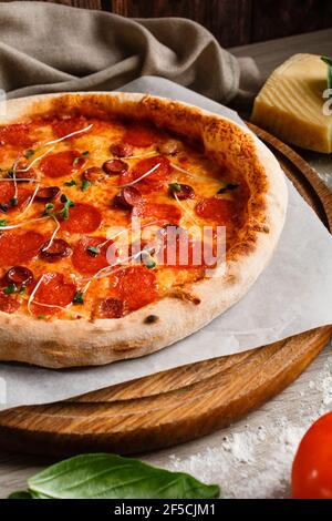 La pizza au pepperoni se trouve sur une planche ronde en bois. Photo pour le menu. Banque D'Images