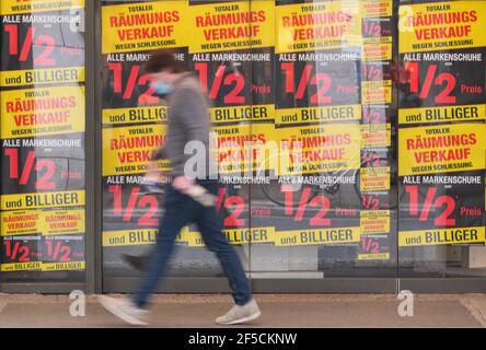 Berlin, Allemagne. 25 mars 2021. Un piéton portant un masque de visage marche après les annonces de vente d'un magasin à Berlin, capitale de l'Allemagne, le 25 mars 2021. Les infections quotidiennes par COVID-19 en Allemagne ont fortement augmenté avec l'enregistrement de 22,657 nouveaux cas en une journée, environ 5,100 il y a plus d'une semaine, a déclaré jeudi l'Institut Robert Koch (RKI). Le taux d'incidence de la COVID-19 sur sept jours dans le pays est également passé de 108.1 pour 100,000 000 personnes la veille à 113.3 jeudi, selon l'agence fédérale de contrôle et de prévention des maladies. Credit: Stefan Zeitz/Xinhua/Alay Live News Banque D'Images