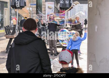 Berlin, Allemagne. 25 mars 2021. On regarde un interprète faire des bulles de savon à Berlin, capitale de l'Allemagne, le 25 mars 2021. Les infections quotidiennes par COVID-19 en Allemagne ont fortement augmenté avec l'enregistrement de 22,657 nouveaux cas en une journée, environ 5,100 il y a plus d'une semaine, a déclaré jeudi l'Institut Robert Koch (RKI). Le taux d'incidence de la COVID-19 sur sept jours dans le pays est également passé de 108.1 pour 100,000 000 personnes la veille à 113.3 jeudi, selon l'agence fédérale de contrôle et de prévention des maladies. Credit: Stefan Zeitz/Xinhua/Alay Live News Banque D'Images