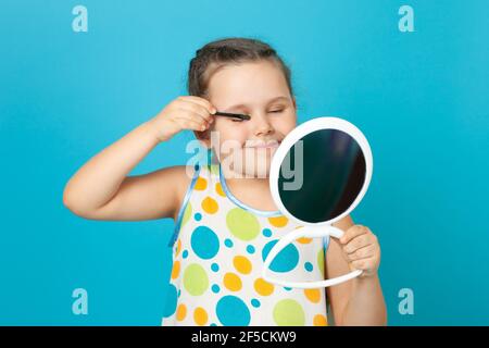 portrait d'une fille heureuse et souriante dans une robe blanche applique l'ombre verte brillante des yeux et se rend isolé sur un fond bleu Banque D'Images