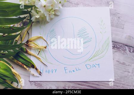 Texte de félicitations du jour de la terre et dessin de la planète avec décor floral sur fond blanc en bois Banque D'Images