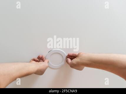 Un électricien installe un projecteur LED au plafond. Banque D'Images