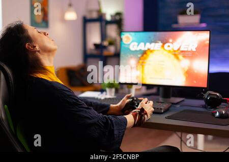 Joueur Femme gagnant jeu de tir de l'espace en utilisant des lunettes de réalité virtuelle jouer à des jeux avec joystick moderne. Les joueurs professionnels diffusent des jeux vidéo en ligne avec de nouveaux graphismes sur un ordinateur puissant Banque D'Images