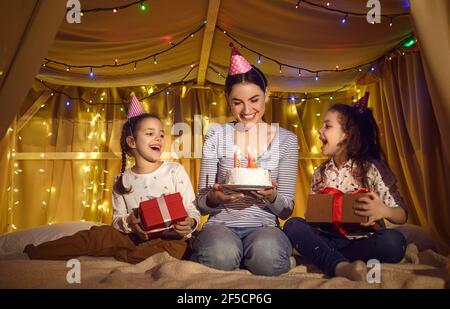 Une jeune mère heureuse reçoit un gâteau et des cadeaux d'anniversaire de sa part de jolies petites filles Banque D'Images