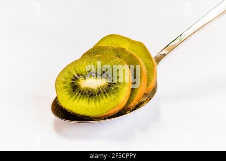 Gros plan de tranches de fruits Kiwi sur une cuillère argentée sur une nappe blanche, Londres, Royaume-Uni Banque D'Images