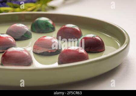 Bonbons au chocolat trempé à la main de collection avec un corps peint brillant sur une plaque ronde avec un fond flou et des éléments bokeh. Stock photog Banque D'Images