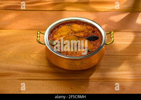 Seer curry de poisson, curry traditionnel de poisson indien, kerala spécial, arrangé dans un bol de service de cuivre garni de malabar tamarin et de chil vert frais Banque D'Images